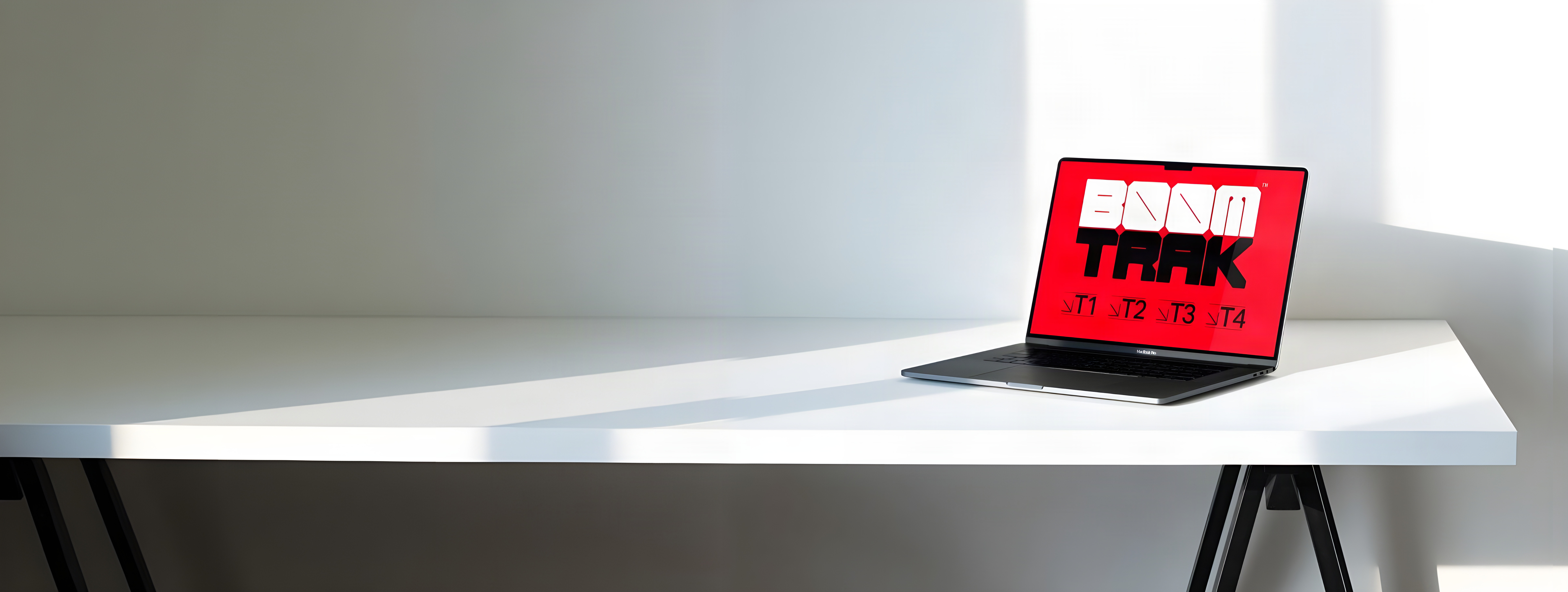 A laptop on a white desk, with BoomTrak on the screen.